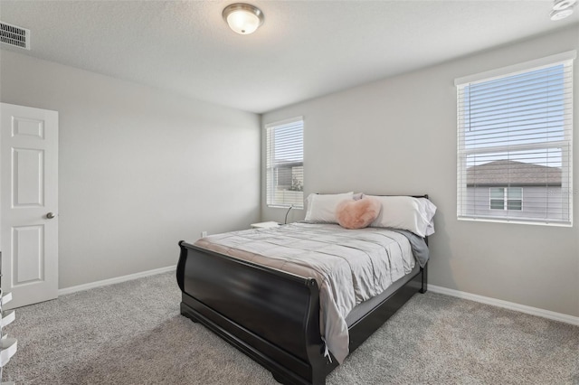 bedroom featuring light carpet, baseboards, visible vents, and a textured ceiling