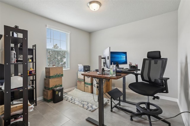 office space featuring a textured ceiling, light tile patterned floors, and baseboards