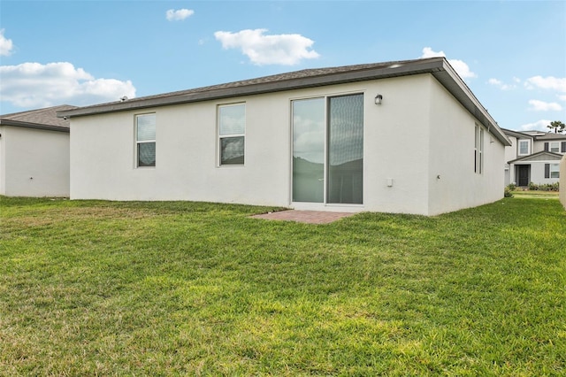 rear view of house with a lawn and stucco siding