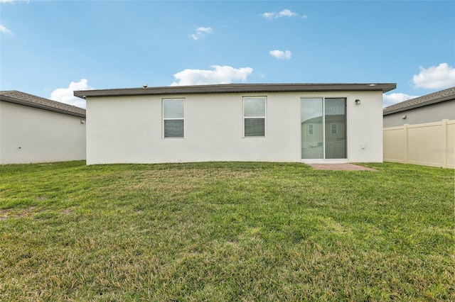 back of property with a yard, fence, and stucco siding