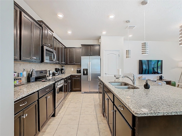 kitchen with stainless steel appliances, a sink, visible vents, dark brown cabinets, and a center island with sink