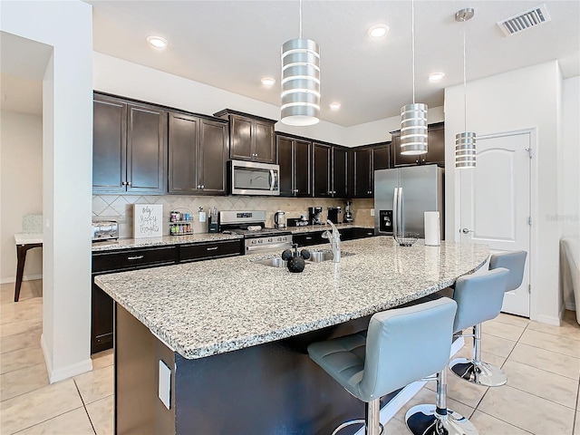 kitchen featuring hanging light fixtures, visible vents, a kitchen island with sink, and appliances with stainless steel finishes