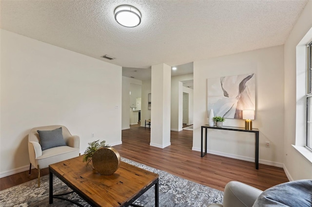 interior space with a textured ceiling, wood finished floors, visible vents, and baseboards