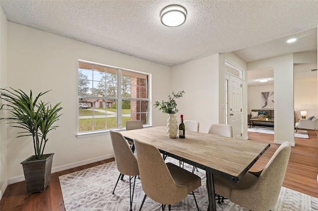 dining room featuring a textured ceiling, baseboards, and wood finished floors