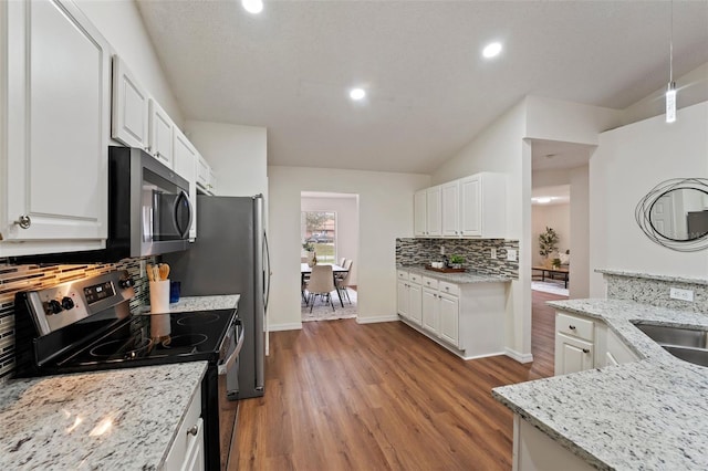 kitchen featuring white cabinets, hanging light fixtures, appliances with stainless steel finishes, light wood-type flooring, and light stone countertops