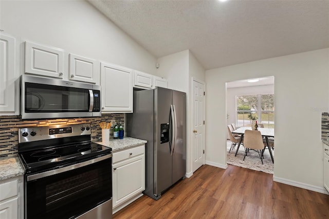 kitchen featuring appliances with stainless steel finishes, dark wood-type flooring, backsplash, and white cabinetry