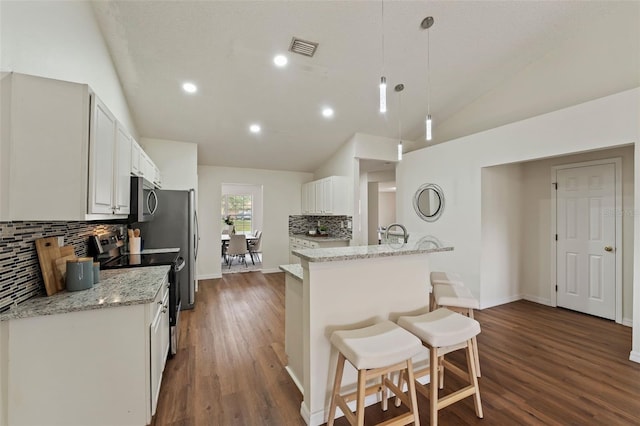 kitchen with light stone counters, decorative light fixtures, stainless steel appliances, white cabinets, and vaulted ceiling