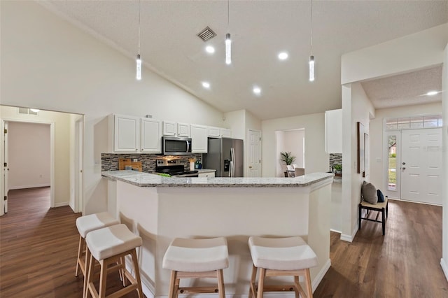 kitchen featuring a peninsula, visible vents, pendant lighting, and stainless steel appliances