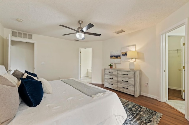 bedroom featuring a textured ceiling, visible vents, and wood finished floors