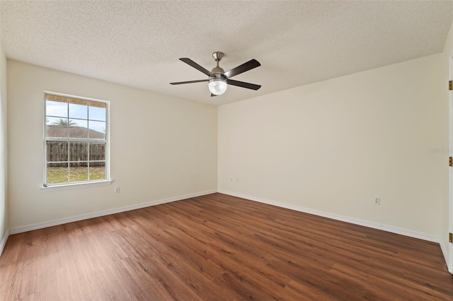 spare room with dark wood-type flooring, ceiling fan, a textured ceiling, and baseboards