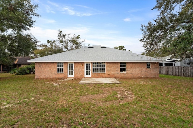 rear view of property with brick siding, fence, a lawn, and a patio