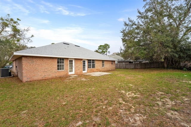 rear view of property featuring a yard, central AC, brick siding, and a fenced backyard