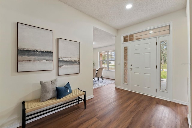 foyer with a textured ceiling, dark wood finished floors, and baseboards