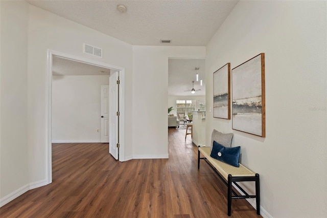 hall with baseboards, visible vents, and dark wood finished floors