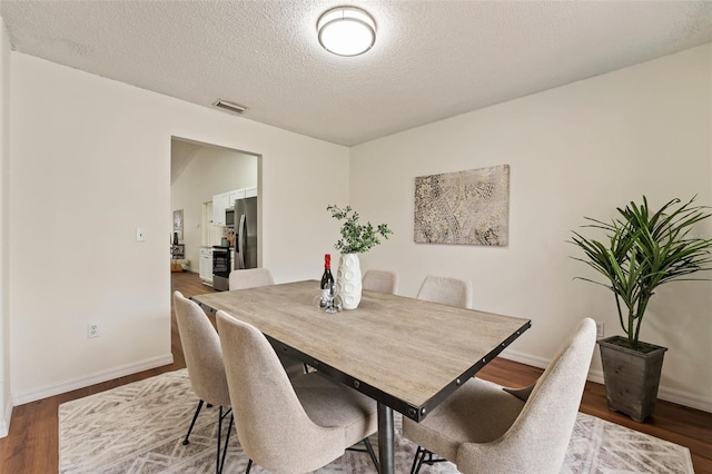 dining area with baseboards, visible vents, and wood finished floors