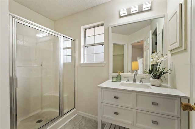 bathroom featuring a textured ceiling, vanity, baseboards, a stall shower, and a walk in closet