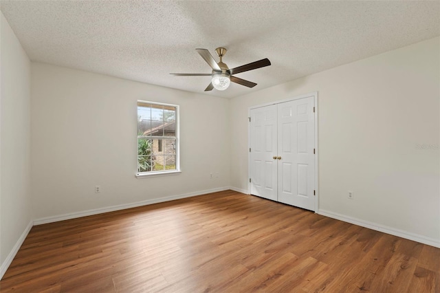 unfurnished bedroom featuring a textured ceiling, baseboards, and wood finished floors