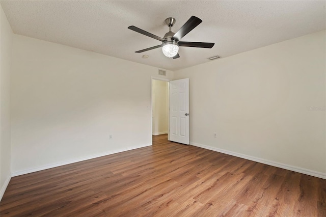 unfurnished room with visible vents, baseboards, a ceiling fan, wood finished floors, and a textured ceiling