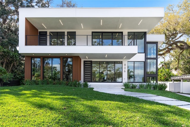 back of house with a yard, a balcony, and stucco siding