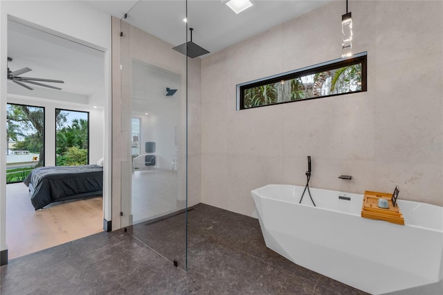 ensuite bathroom featuring a freestanding bath, tile walls, a walk in shower, and a wealth of natural light