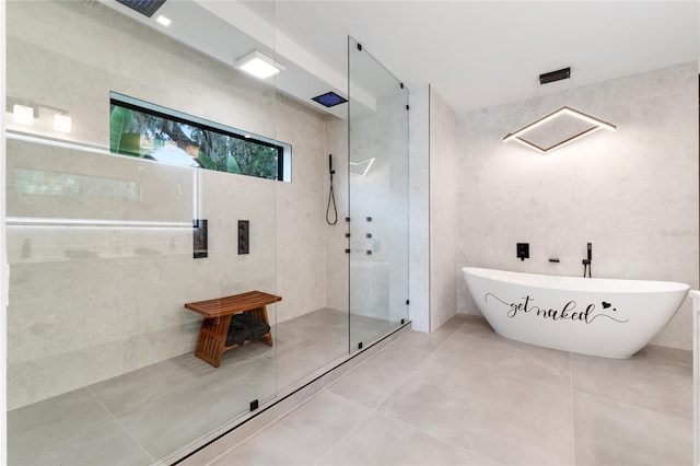 bathroom with a freestanding tub, a tile shower, tile walls, and tile patterned floors