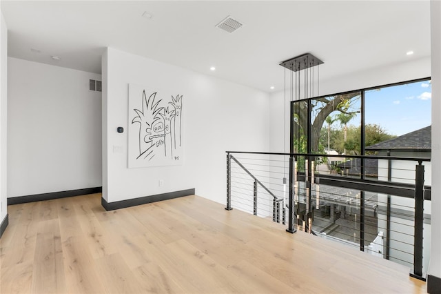 hall featuring recessed lighting, visible vents, wood finished floors, and an upstairs landing