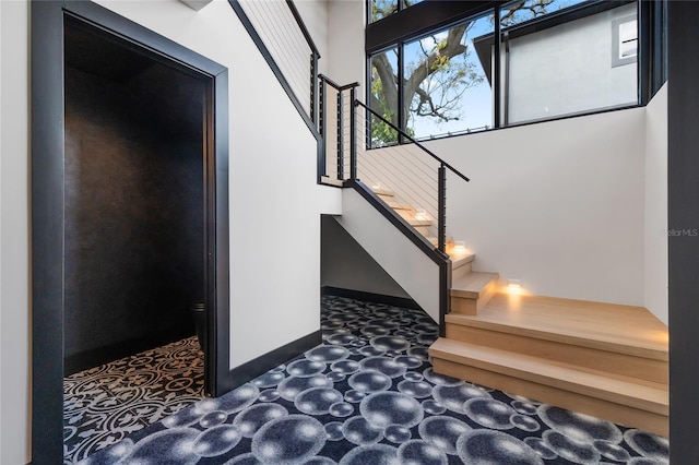 stairway with a towering ceiling and baseboards