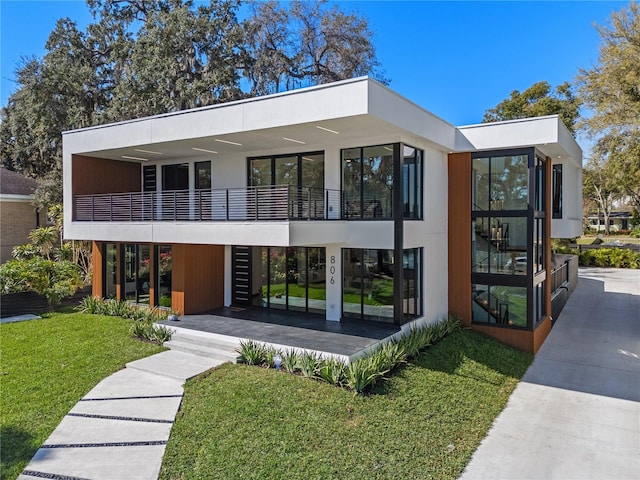 exterior space featuring a lawn, a balcony, and stucco siding