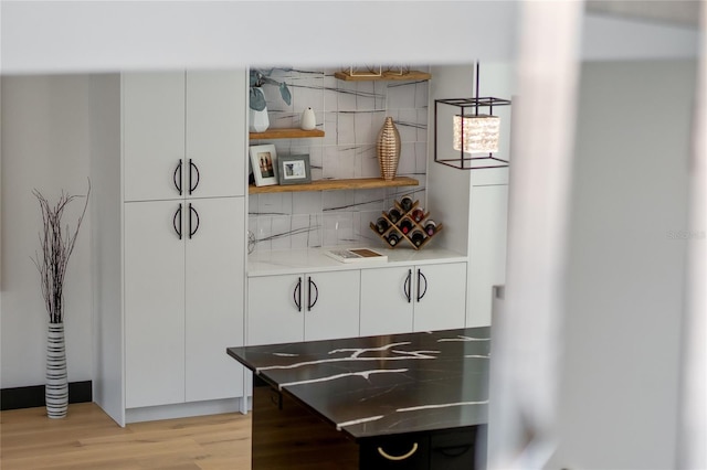 bar featuring light wood-style flooring and backsplash