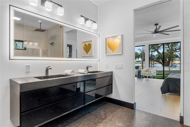 full bathroom with double vanity, a sink, a ceiling fan, and baseboards