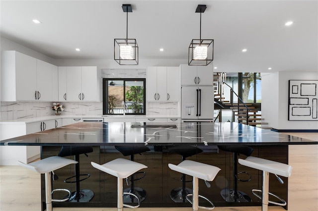 kitchen featuring high end fridge, tasteful backsplash, decorative light fixtures, and white cabinets