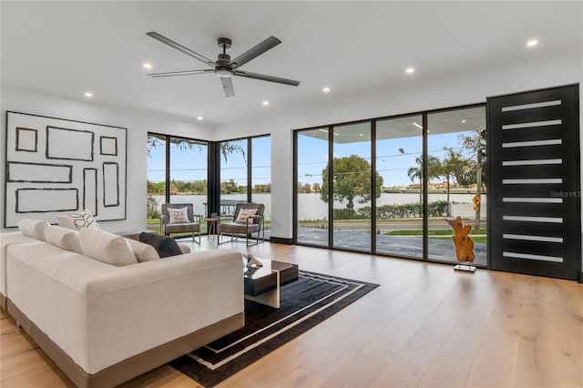 living room featuring recessed lighting, a healthy amount of sunlight, a water view, and light wood-style flooring