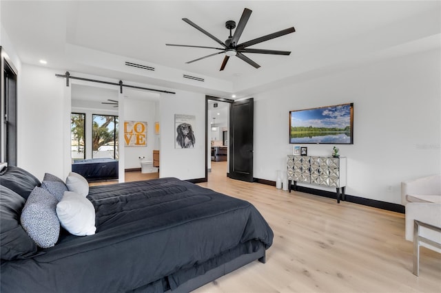 bedroom with baseboards, a barn door, visible vents, and light wood-style floors