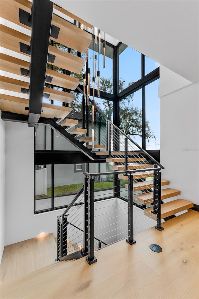 staircase featuring floor to ceiling windows and wood finished floors