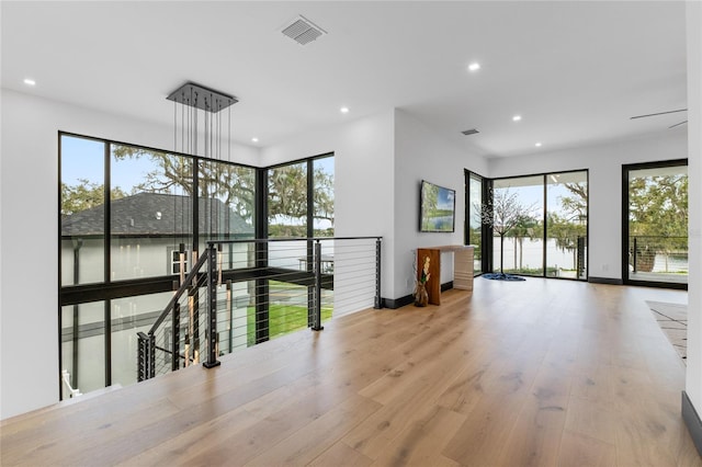 empty room featuring a wealth of natural light, visible vents, wood finished floors, and recessed lighting