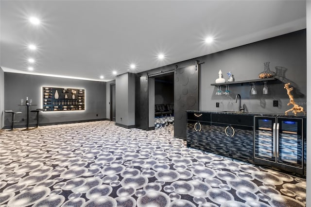 interior space with recessed lighting, a barn door, a sink, wet bar, and beverage cooler