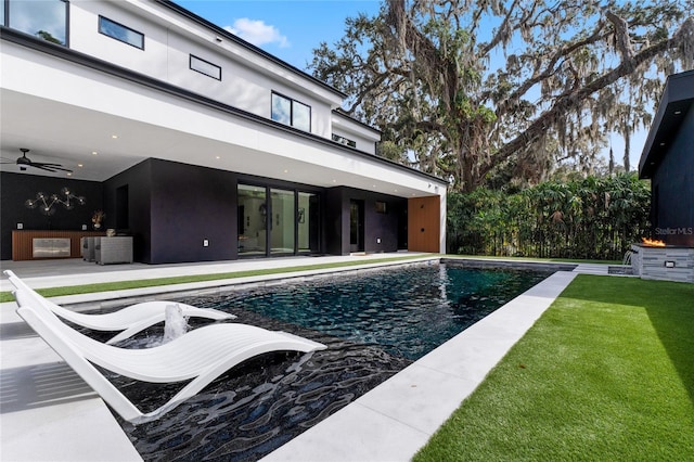 pool featuring a lawn, a patio area, and a ceiling fan