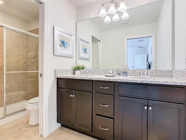 full bathroom with double vanity, a stall shower, toilet, tile patterned floors, and a sink