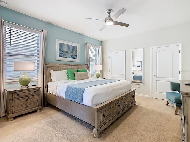 bedroom with light colored carpet, ceiling fan, and baseboards