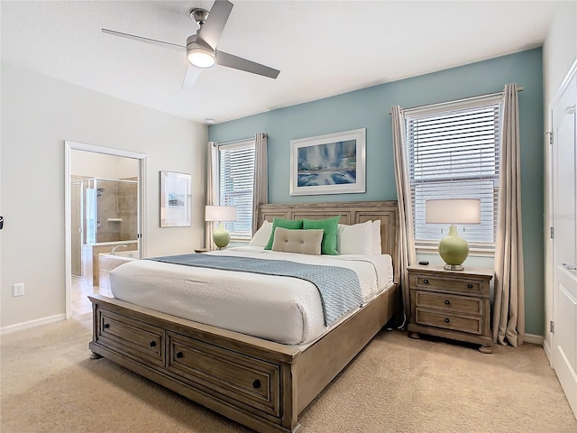 bedroom with a ceiling fan, light colored carpet, ensuite bathroom, and multiple windows