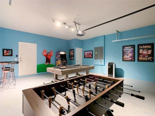 game room featuring a garage, electric panel, and speckled floor