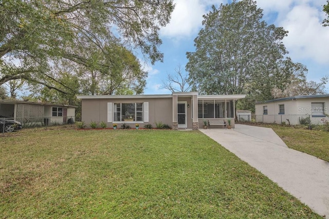 ranch-style house featuring fence, a sunroom, driveway, stucco siding, and a front lawn