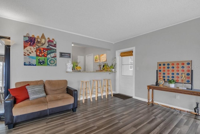 living area featuring ornamental molding, a textured ceiling, baseboards, and wood finished floors