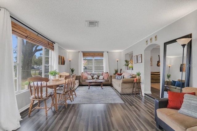 living area with baseboards, visible vents, arched walkways, dark wood finished floors, and a textured ceiling