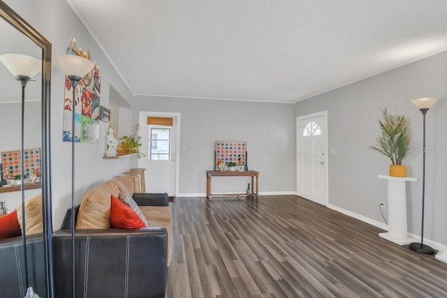 living room featuring a textured ceiling, ornamental molding, dark wood finished floors, and baseboards