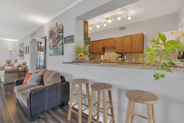 kitchen with visible vents, decorative backsplash, a breakfast bar area, open floor plan, and dark wood-style flooring