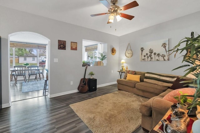 living area with ceiling fan, baseboards, and dark wood-type flooring