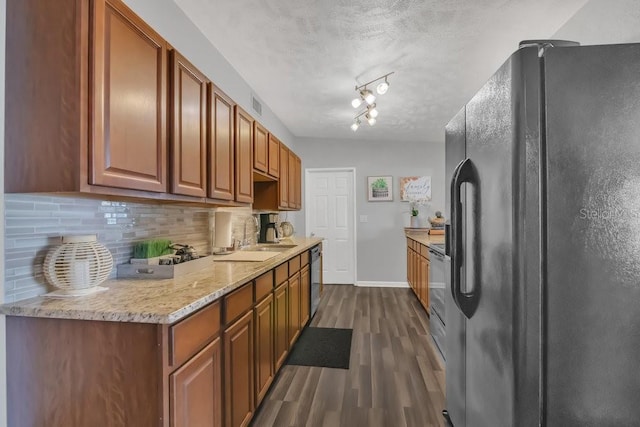 kitchen featuring dark wood-type flooring, a sink, black appliances, tasteful backsplash, and brown cabinetry