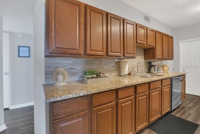 kitchen featuring dark wood-type flooring, a sink, stainless steel dishwasher, brown cabinets, and tasteful backsplash