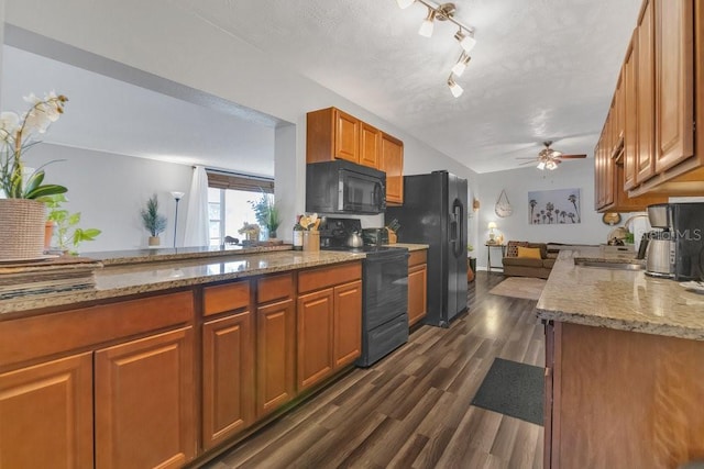 kitchen with a peninsula, black appliances, brown cabinets, and a sink